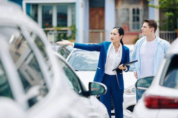 Female manager helping client to choose car in rental service parking - Photo, Image