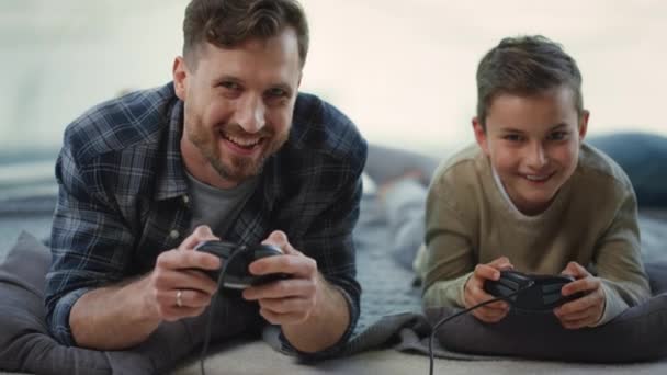Padre e figlio che giocano su console in casa. Genitore e bambino che giocano sulla stazione di gioco - Filmati, video