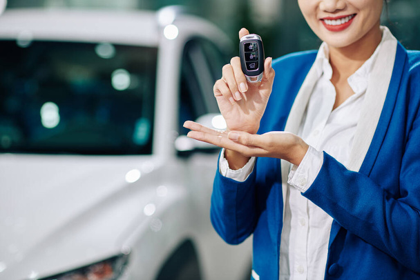 Imagen recortada del gerente de concesionario de automóviles sonriente mostrando las llaves electrónicas - Foto, Imagen