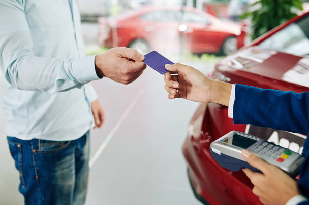 Крупним планом зображення чоловіка, який платить кредитною карткою за прокат автомобіля
 - Фото, зображення