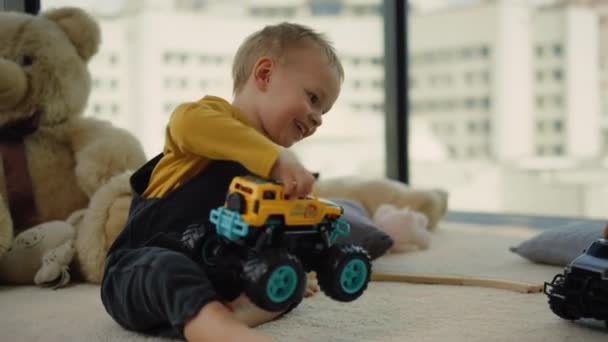 Pikkupoika leikkii leluautoilla tuntemattoman sukulaisen kanssa. Lapsella hauskaa sisätiloissa. - Materiaali, video