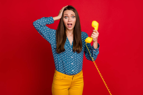 Portrait of attractive worried girl holding in hand receiver news information panic isolated bright red color background - Fotoğraf, Görsel