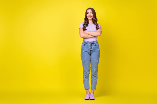 Full length body size view of pretty cheerful wavy-haired girl folded arms looking aside copy space isolated on bright yellow color background - Foto, Imagen