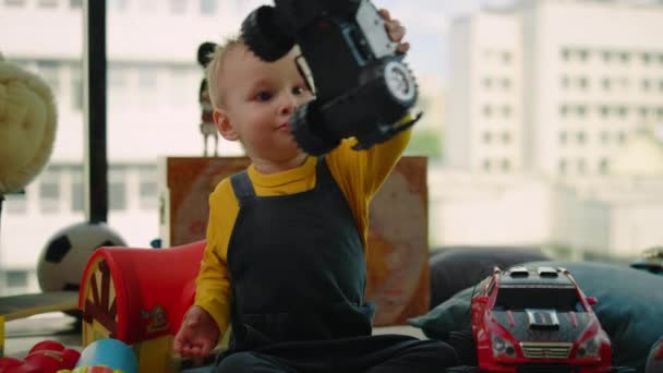 Porträt eines kleinen Jungen, der drinnen Spielzeugauto spielt. Nettes Kind hat Spaß zu Hause. - Filmmaterial, Video
