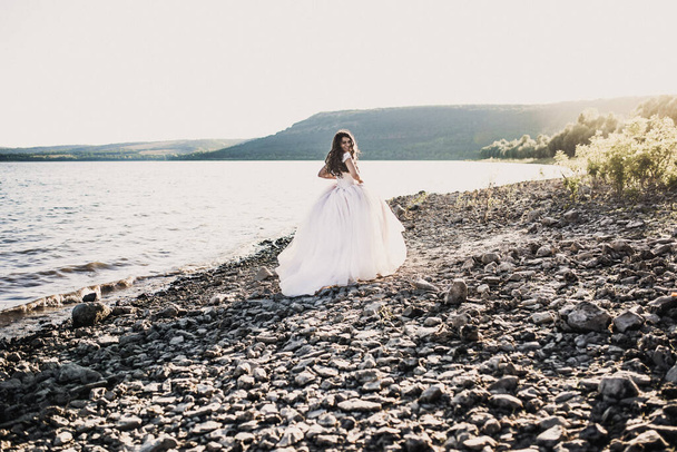 novia en vestido de novia feliz y riendo correr en la orilla del río - Foto, imagen