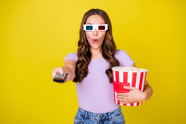 Portrait of attractive amazed funky wavy-haired girl holding corn watching thriller switching channel isolated on bright yellow color background - Foto, Imagen
