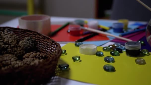Na stole jsou náhodně uspořádané barvy, tužky, štětce, barevný papír - Záběry, video