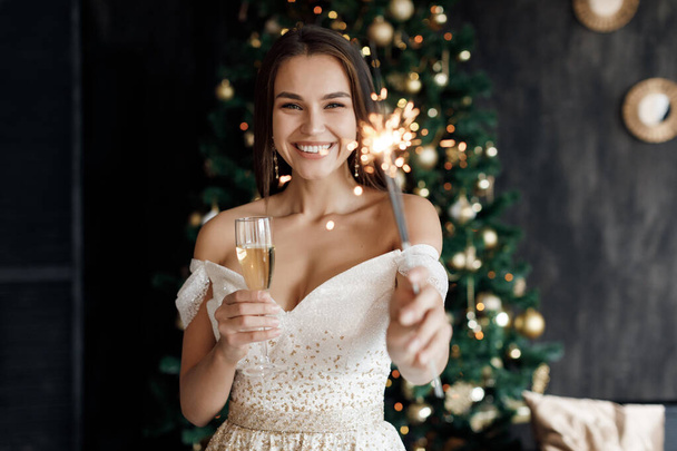 Christmas and new year concept Fashion young beautiful woman in luxury dress. . girl with sparlight lights and champagne - Foto, imagen