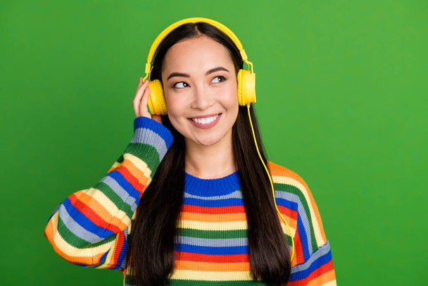 Close-up portrait of attractive cheerful dreamy pensive girl listening music melody isolated over bright green color background - Valokuva, kuva