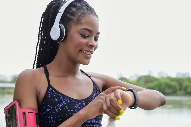 Poseren jonge zwarte sportvrouw wijzen op fitness tracker op haar pols - Foto, afbeelding