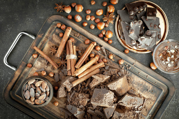 Σκούρα σοκολάτα στο φόντο των κόκκων κακάο και τα στοιχεία για την κουζίνα - Φωτογραφία, εικόνα