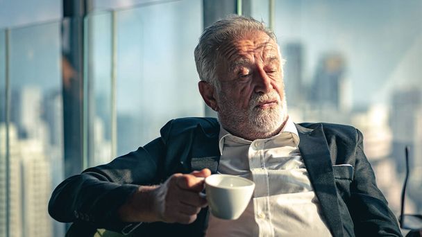 Tired senior businessman drink a cup of coffee indoors. - Photo, Image