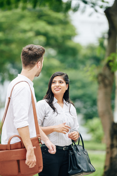 uśmiechnięta indyjska bizneswoman patrząc na jej biorąc kolegę, gdy stoją w parku - Zdjęcie, obraz