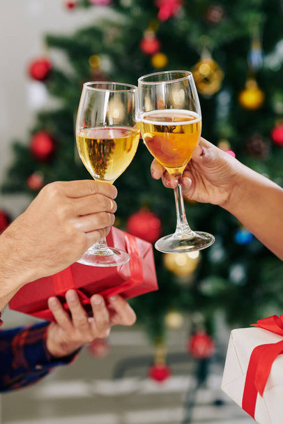Couple toasting with champagne glasses and exchanging Christmas presents at party - Foto, Imagem