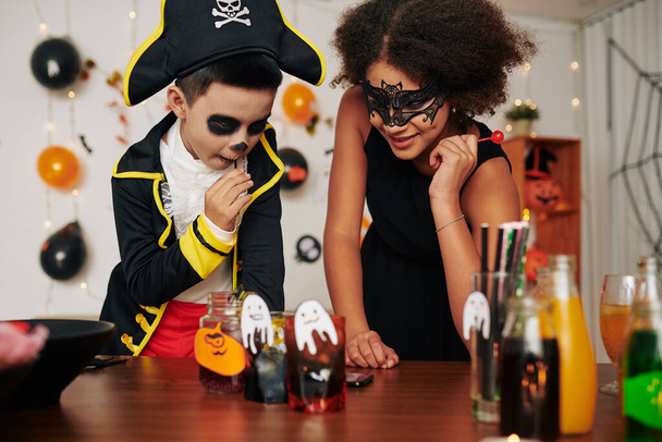 Ενθουσιασμένα παιδιά επιλέγουν τι ποτό να δοκιμάσουν στο Halloween party - Φωτογραφία, εικόνα