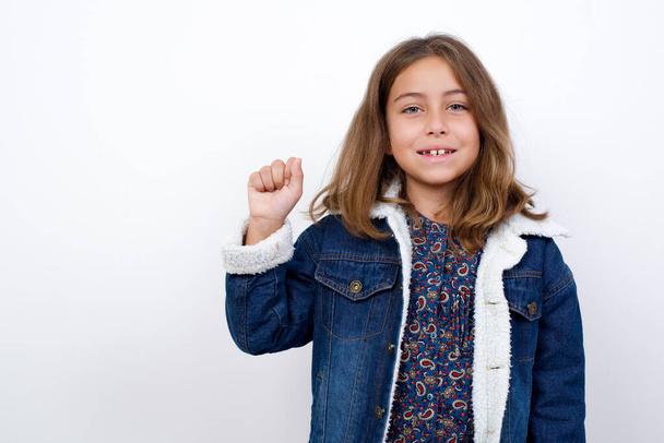 Little caucasian girl with beautiful blue eyes wearing denim jacket standing over isolated white background pointing up with fingers number ten in Chinese sign language Shi - Foto, imagen