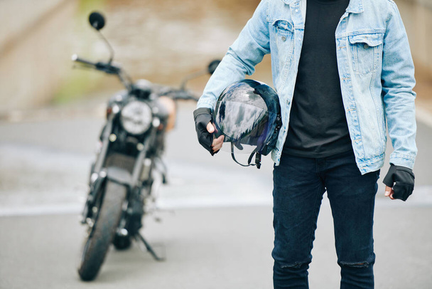 Cropped image of motorcyclist standing with helmet in hands - Photo, Image