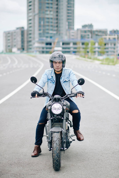 Poważny młody Azjata w kasku jazda motocyklem na autostradzie - Zdjęcie, obraz