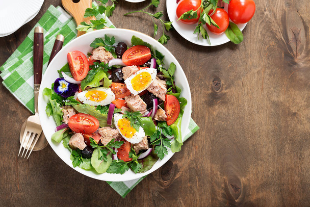 Салат из рыбы тунца с салатом, помидорами, яйцами и оливками. - Фото, изображение