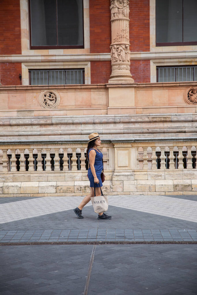 Vista Lateral de uma Mulher de Vestido Azul Andando Fora de um Edifício Clássico - Foto, Imagem
