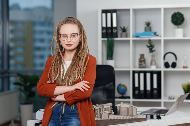 Retrato de mujer de negocios con estilo exitoso con rastas cerca de su lugar de trabajo con maqueta de futuro edificio. - Foto, imagen