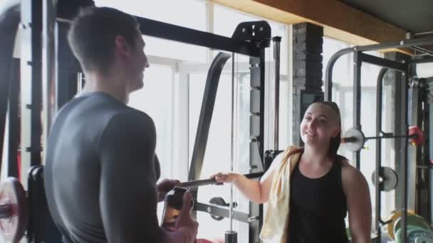Dva atraktivní atletické přátelé muž a žena mluví v tělocvičně po tréninku - Záběry, video
