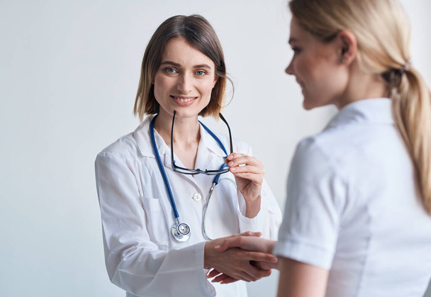 beautiful woman doctor with stethoscope shaking hands with female patient - Photo, Image