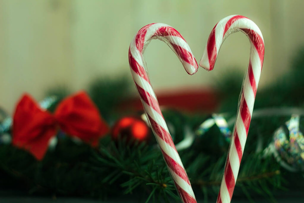 Białe i czerwone lizaki na tle zabawek świątecznych na drzewie - Zdjęcie, obraz
