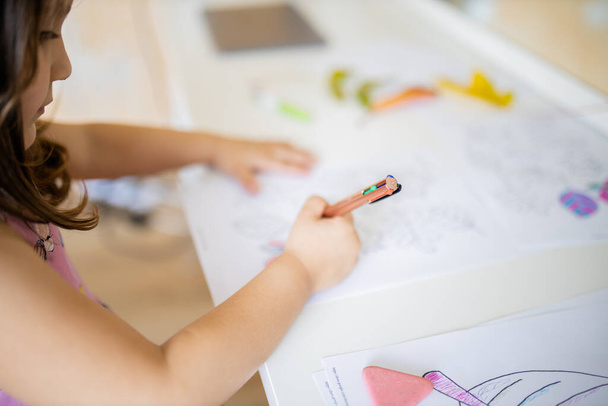 Kleines Mädchen färbt mit einem Stift verschiedene Arten von Blättern auf ein Blatt Papier - Foto, Bild