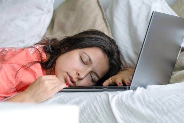 The girl fell asleep on a laptop while working. Sleep during working hours. Freelancer problems. - 写真・画像