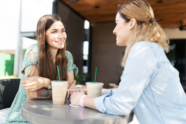 Όμορφες Ισπανίδες νεαρές γυναίκες και μια χαριτωμένη Καυκάσια νεαρές γυναίκες που φαίνονται χαρούμενες σε ραντεβού για καφέ.  - Φωτογραφία, εικόνα