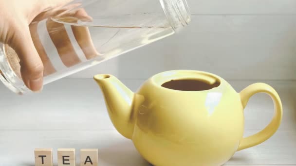Stop mozgás animáció, amelyben a folyamat főzés tea folyik, vizet öntenek a sárga teáskanna, majd egy szelet citrom repül a teáskanna, majd a tea zsák és a teáskanna táncol a végén. - Felvétel, videó