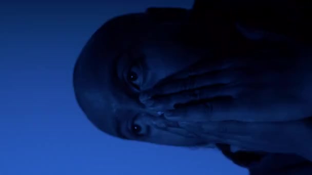 Dospělý muž tření tvář s rukama v tísni s červenou modrou Strobe osvětlení. Svislé video, uzamčeno - Záběry, video