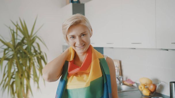 Junge blonde Frau mit Regenbogenfahne in ihrer Wohnung - Foto, Bild