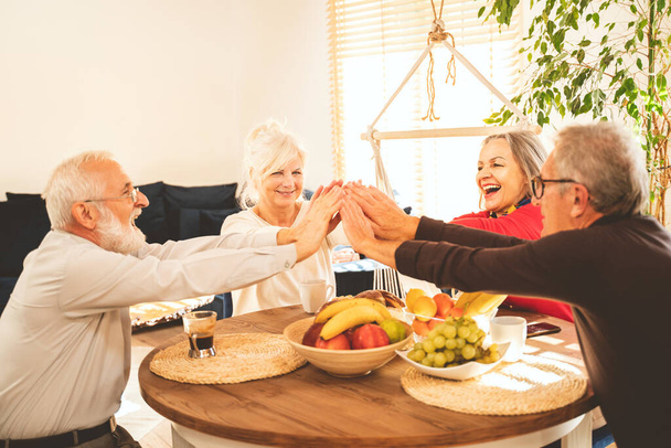 Group of senior people celebrating success together at home. Happy retirement concept. - 写真・画像