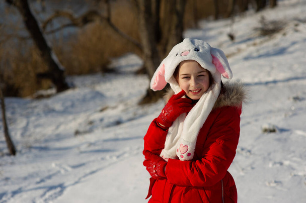 Little toddler girl in beautiful warm red outfit playing outdoors in the snow. Girl in a red jacket on the street in winter. A school age girl 9 or 10 years old in winter. - Photo, Image