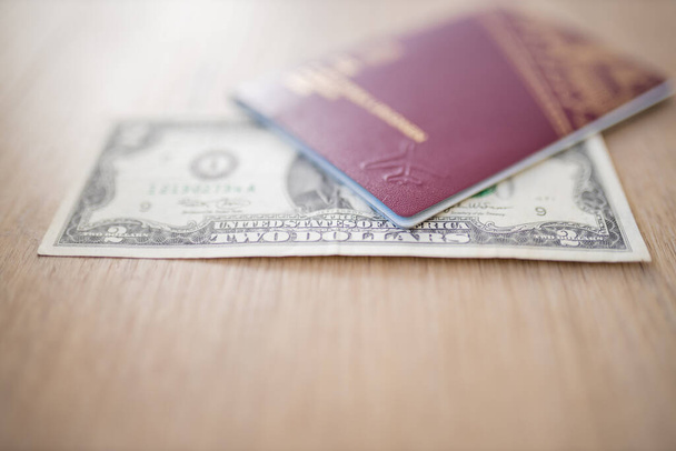 Due dollari Bill parzialmente all'interno di un passaporto svedese su un tavolo di legno - Foto, immagini