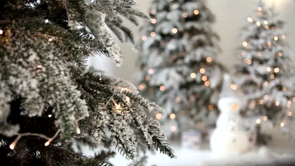 Prachtig nieuwjaarsinterieur, takken van een kerstboom close-up. Defocused kerstboom met verlichting en ornamenten. Wazig silhouet van een kerstboom met gloeiende lichten. - Video
