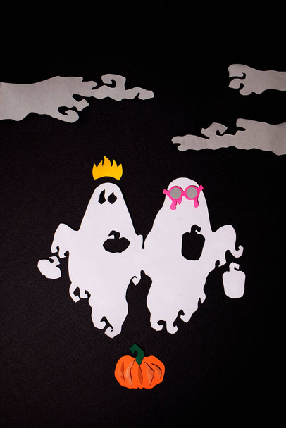Twee feestelijke geesten vliegen over de pompoen tussen de mist op een zwarte achtergrond - Foto, afbeelding