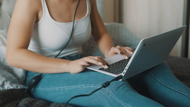 Giovane donna che utilizza il computer portatile nella sua camera da letto. Freelance che lavora comodamente da casa sua - Foto, immagini