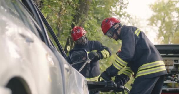 Firemen opening crushed door of car - Footage, Video