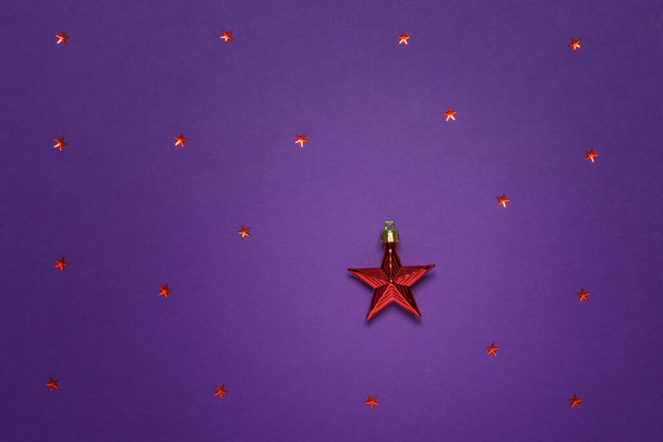 Одна большая красная звезда и много маленьких на фиолетовом фоне. - Фото, изображение