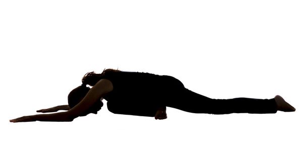 silhouet van een jonge vrouw in duif pose in yoga - Foto, afbeelding