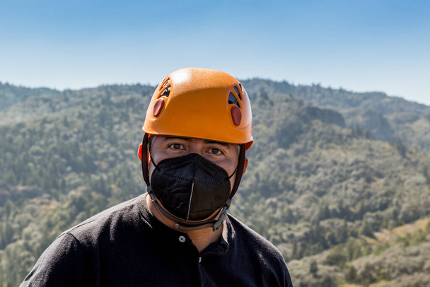 Primer plano de un escalador masculino en la cima de la montaña con una máscara facial - Foto, Imagen