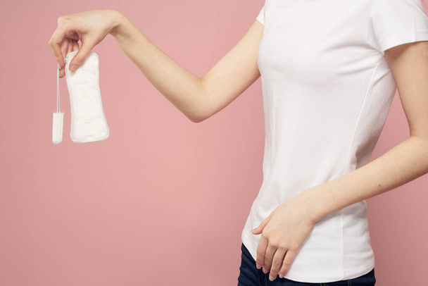 Girl with a pad and tampons in hand pink background menstruation critical days hygiene - Photo, Image
