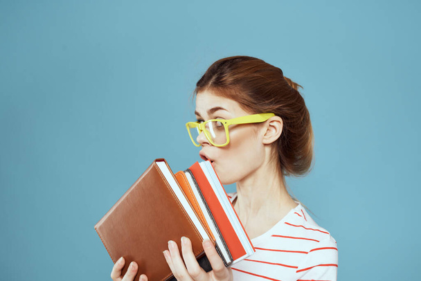 Female student with notepads and glasses hairstyle on her head teacher model blue background - Photo, Image