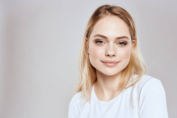 Cheerful blonde woman in white t-shirt cropped view light background - Foto, imagen
