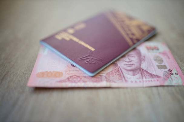 Cento Thai Baht Bill parzialmente all'interno di un passaporto svedese - Foto, immagini