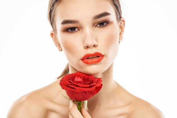 Όμορφη γυναίκα με κόκκινο τριαντάφυλλο κοντά μακιγιάζ πρόσωπο γυμνοί ώμοι πορτρέτο - Φωτογραφία, εικόνα