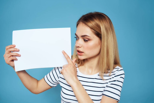 Woman holding sheet of paper striped T-shirt Copy Space cropped view blue background - 写真・画像
